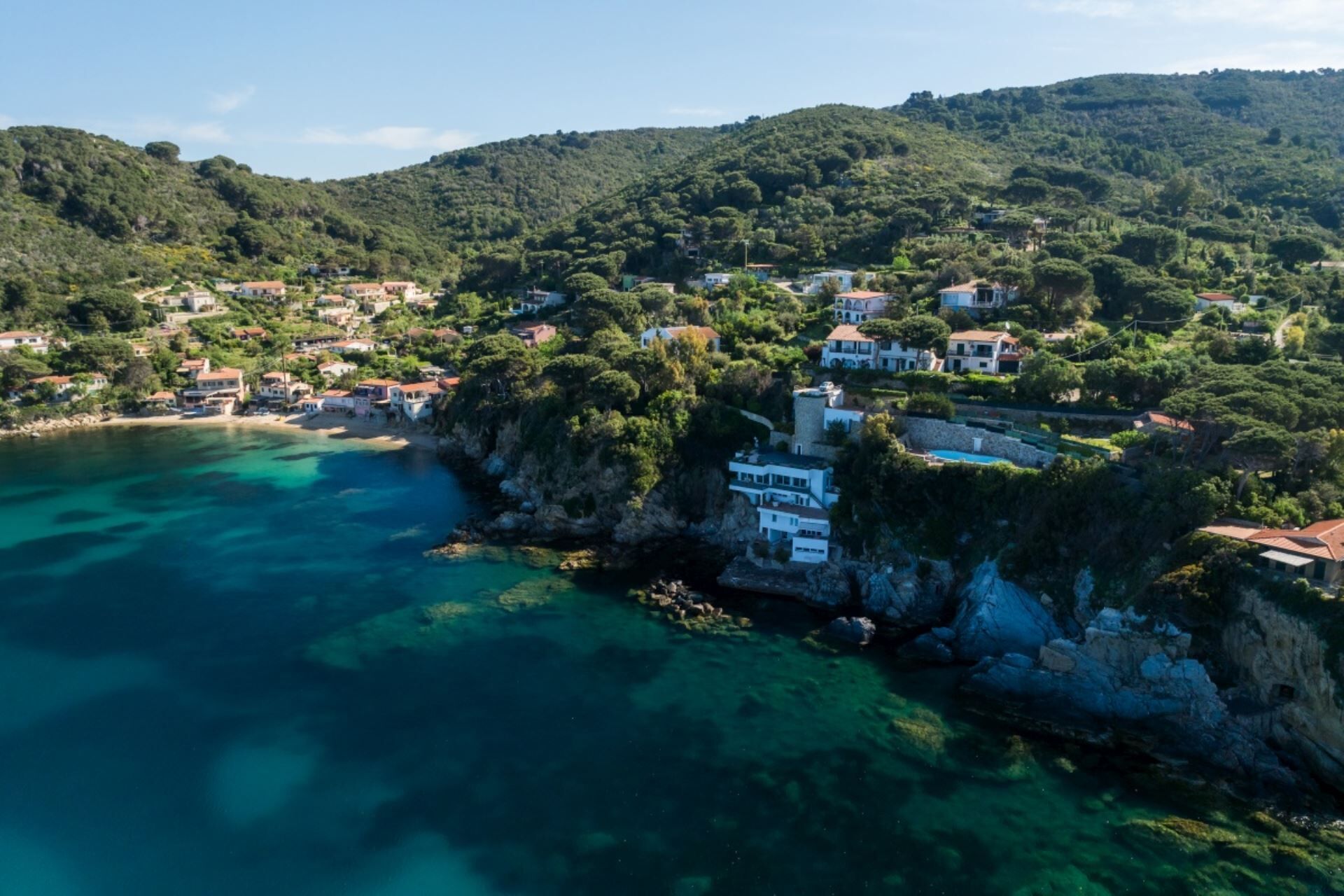 Un village côtier dont les maisons sont construites sur des falaises surplombant des eaux d’un bleu limpide.