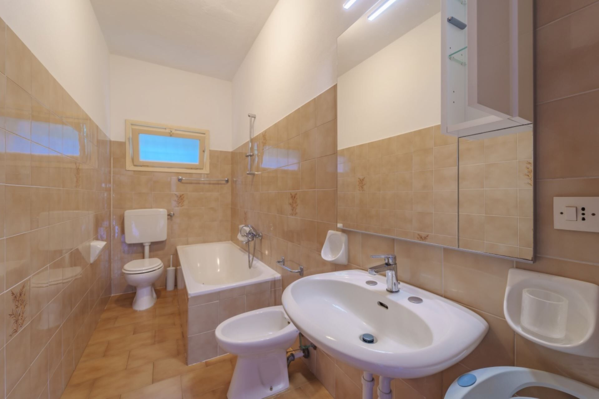 A modern bathroom with a toilet, bidet, bathtub, and sink.
