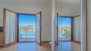A spacious room with a large sliding glass door leading to a balcony with a scenic view of hills and a body of water.