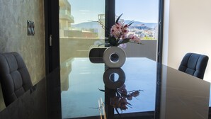 Ein moderner Konferenzraum mit einem Glastisch, einer Vase mit rosa Blumen und Blick auf eine Stadtlandschaft durch große Fenster.