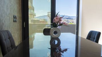 Une salle de conférence moderne, dotée d’une table en verre, d’un vase rempli de fleurs roses et offrant une vue sur le paysage urbain grâce à de grandes fenêtres.