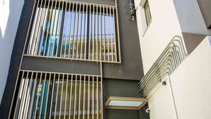 A modern building with multiple floors, large windows with metal bars, and a clean, geometric architectural design.