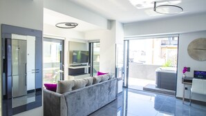 Ein modernes Wohnzimmer mit einem grauen Sofa, einem Flachbildfernseher und einer Glastür, die auf einen Balkon führt.