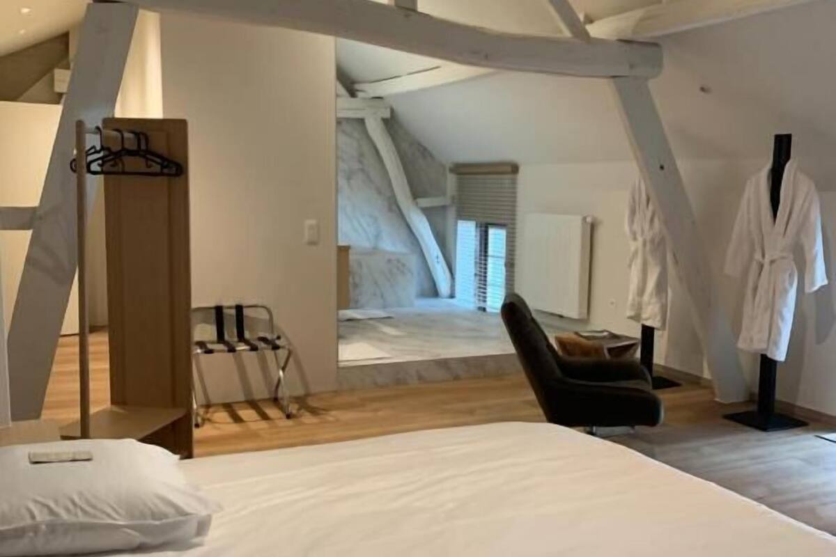 A bedroom with a large bed, a chair, and a wooden structure.