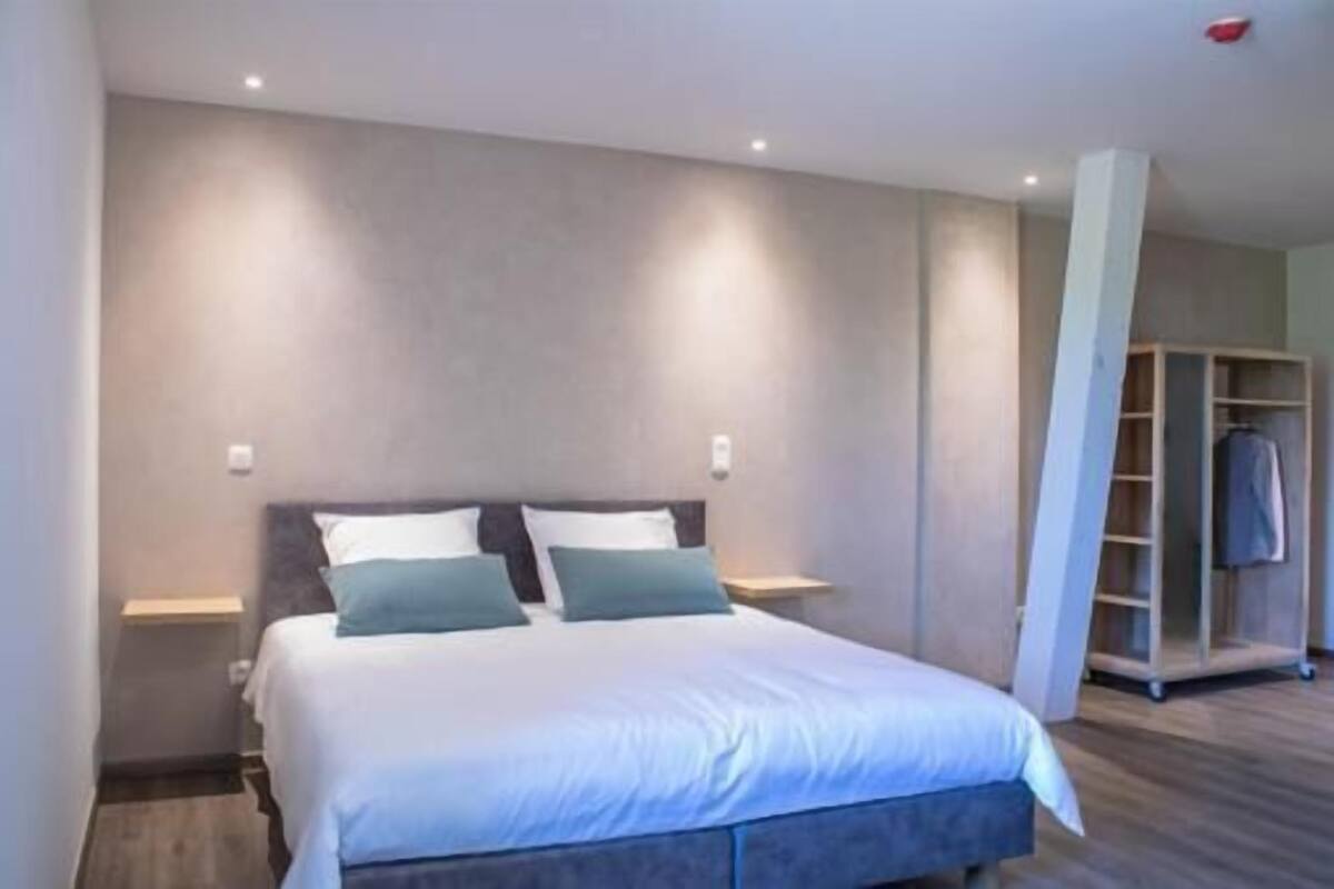 A modern hotel room with a large bed, bedside tables, and a built-in wardrobe.