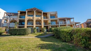 A multi-story hotel with balconies, a central courtyard, and a well-maintained lawn. - Le Hameau (K3 122) by Interhome (Agay Village Cap Esterel)