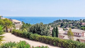 A coastal view with Mediterranean-style buildings, a clear sky, and a view of the sea.