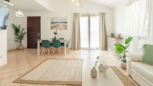 A modern living room with a dining area, featuring a large rug, a coffee table, and a sofa.