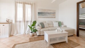 A living room with a sofa, a coffee table, a plant, and a painting on the wall.