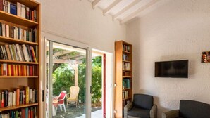 A living room with a fireplace, a television mounted on the wall, and a sliding glass door leading to an outdoor patio. - Villa Irène by Interhome (Bravone)