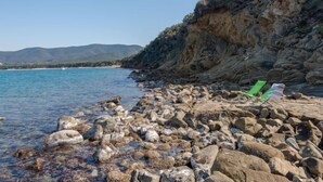 A rocky shoreline with a green chair on the rocks.