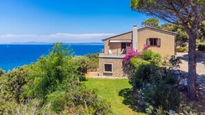 A coastal house with a stone facade, a small balcony, and a view of the sea.