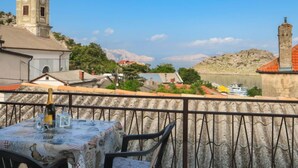 A terrace with a table set for dining, overlooking a town with a church tower and a mountain in the background. - Apartment Nena by Interhome (Sveti Juraj)