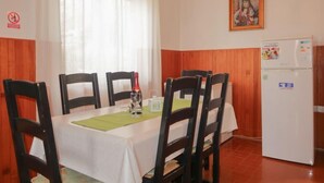 A dining area with a table set for four, chairs, a bottle of wine, and a refrigerator. - Apartment Nena by Interhome (Sveti Juraj)