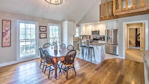 A spacious dining area with a wooden table and chairs, a chandelier, and large windows. - Bright ‘Green Gables’ Cabin: Hike, Swim & BBQ (Lewisburg)