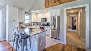 A modern kitchen with white cabinets, stainless steel appliances, and a marble island with bar stools. - Bright ‘Green Gables’ Cabin: Hike, Swim & BBQ (Lewisburg)