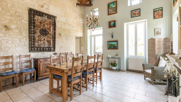 A dining area with a wooden table and chairs, stone walls, and a chandelier. - Elegant Château Escape (Cezac)