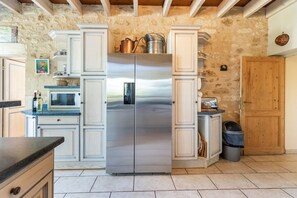 Eine Küche mit einem Edelstahl-Kühlschrank mit zwei Türen, weißen Schränken, einer Mikrowelle und einer Holztür.