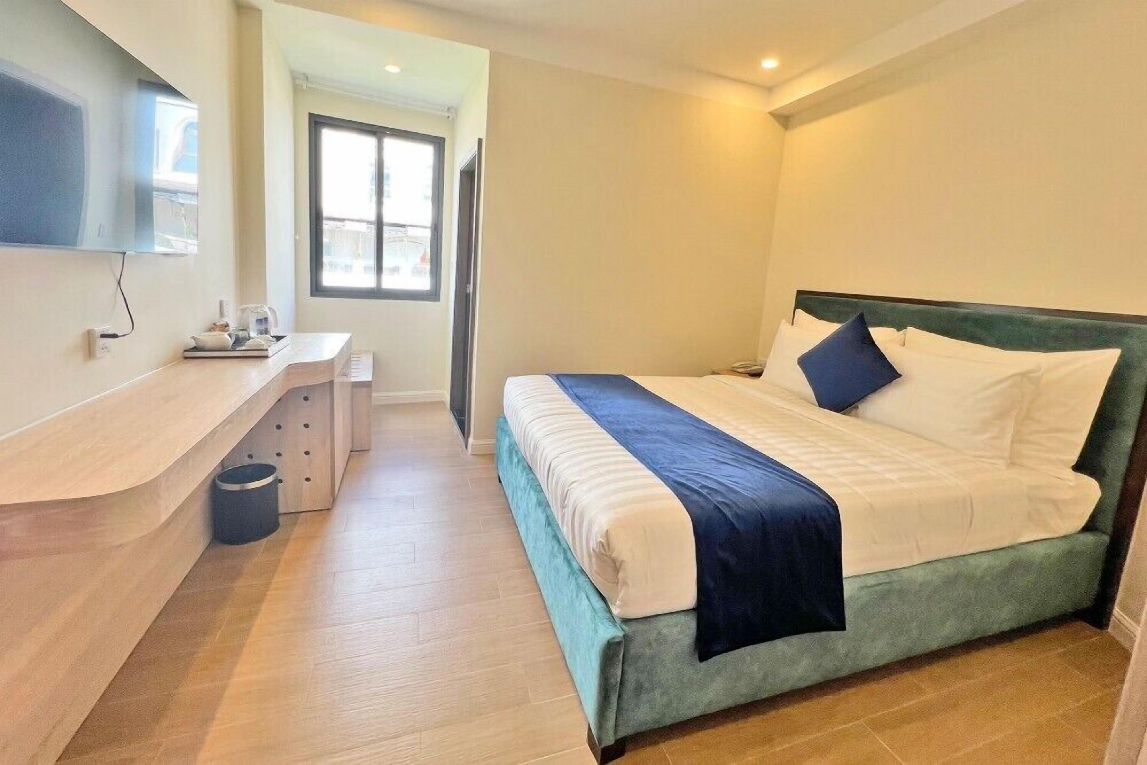 A bedroom with a bed, a bedside table, a chair, and a window.