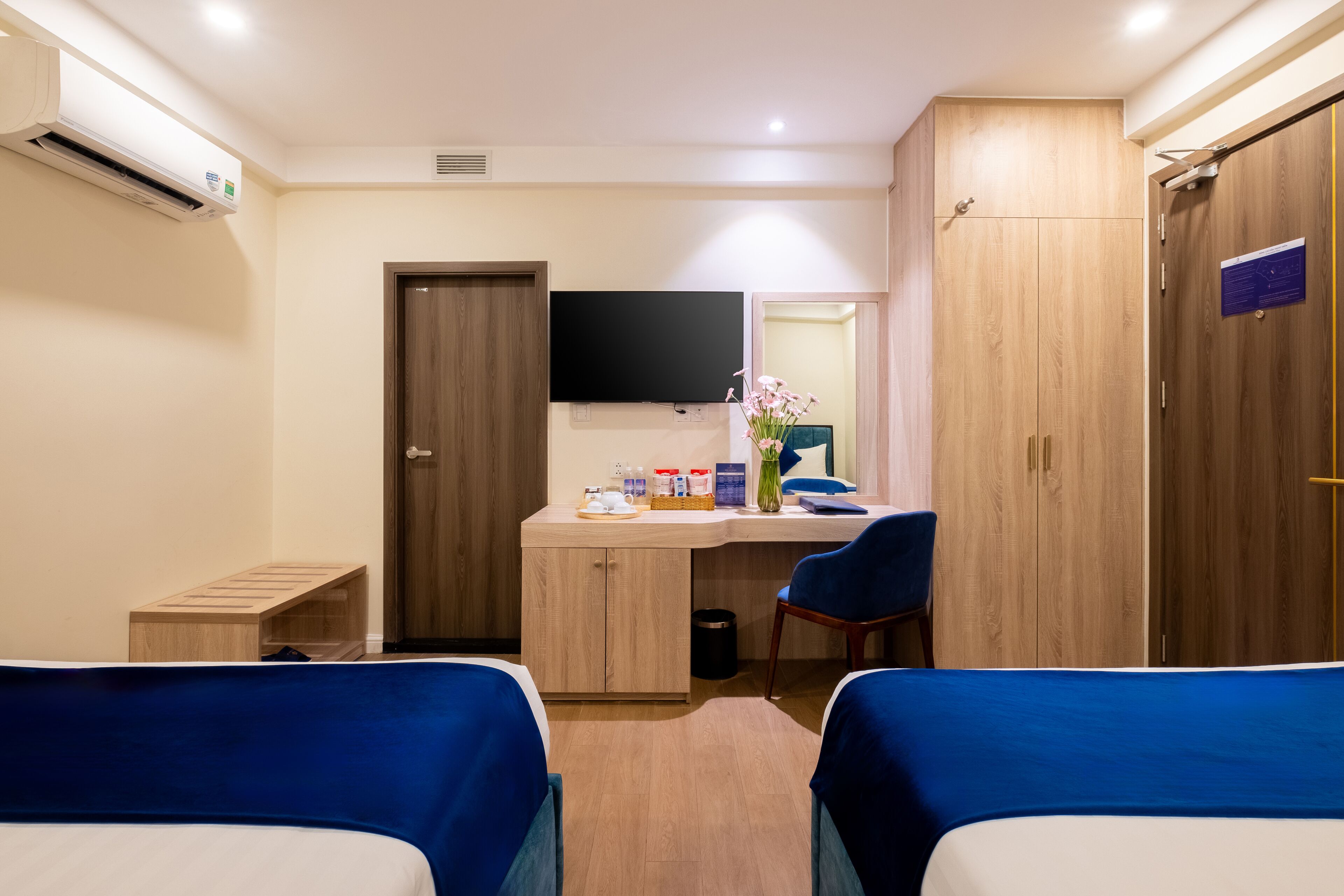 A hotel room with two beds, a desk, a chair, a TV, and a wardrobe.
