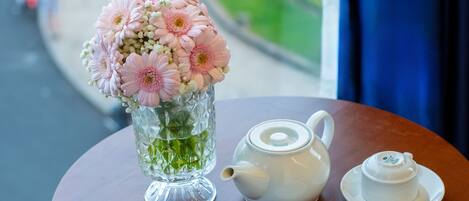 Una mesa con un jarrón de flores, una tetera y dos tazas.