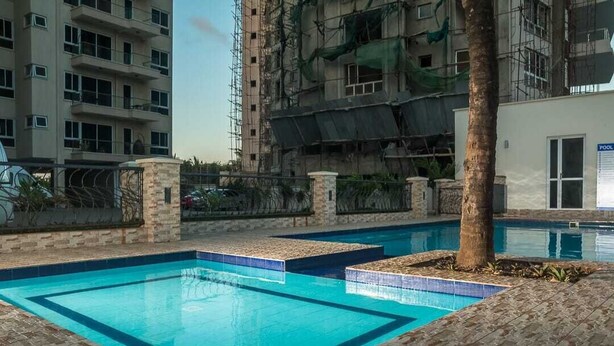 Une piscine dont le bord est revêtu de carreaux, entourée d  ’une terrasse en briques et agrémentée d’un palmier.