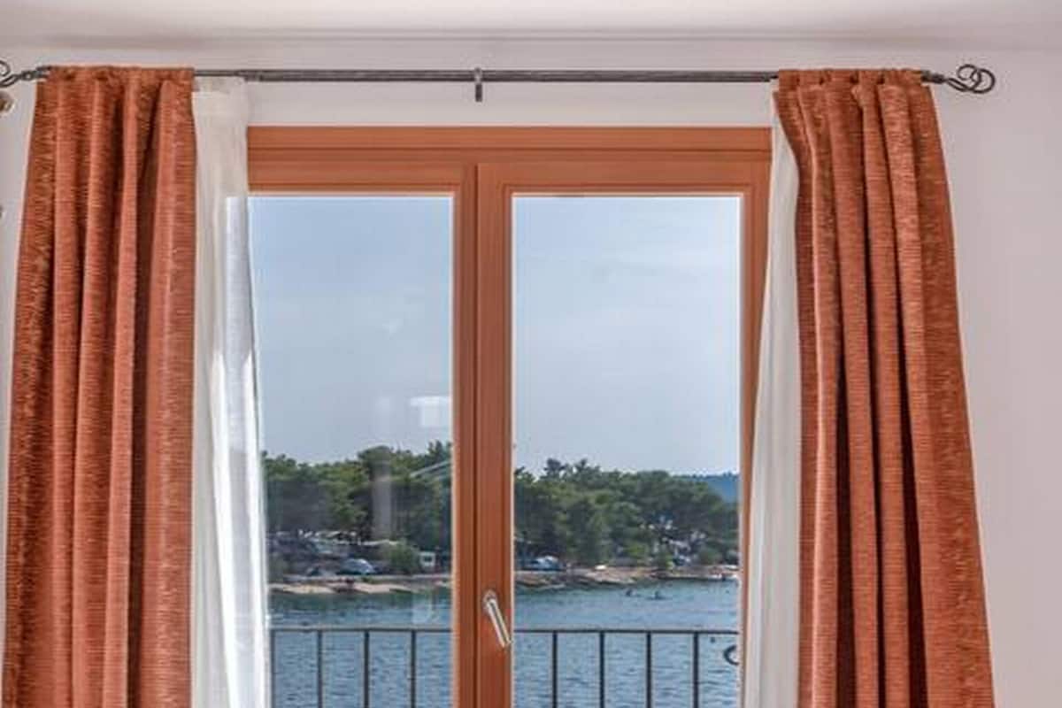 Habitación con vista a una masa de agua a través de un vidrio con barandilla de metal.