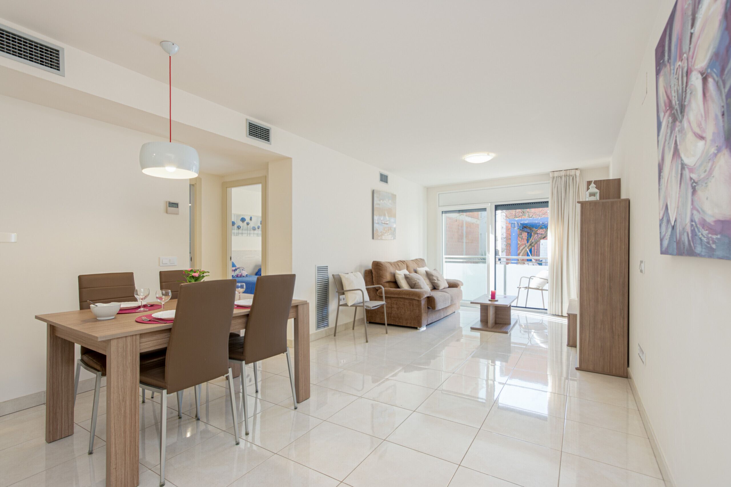 A modern living room with a dining area, a sofa set, and a large window with curtains.