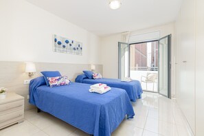 A hotel room with two beds, a balcony, and a view of the city.