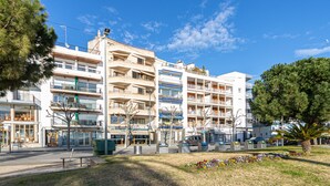 Un immeuble à plusieurs étages doté de balcons, d’un espace de stationnement et d’une fontaine.