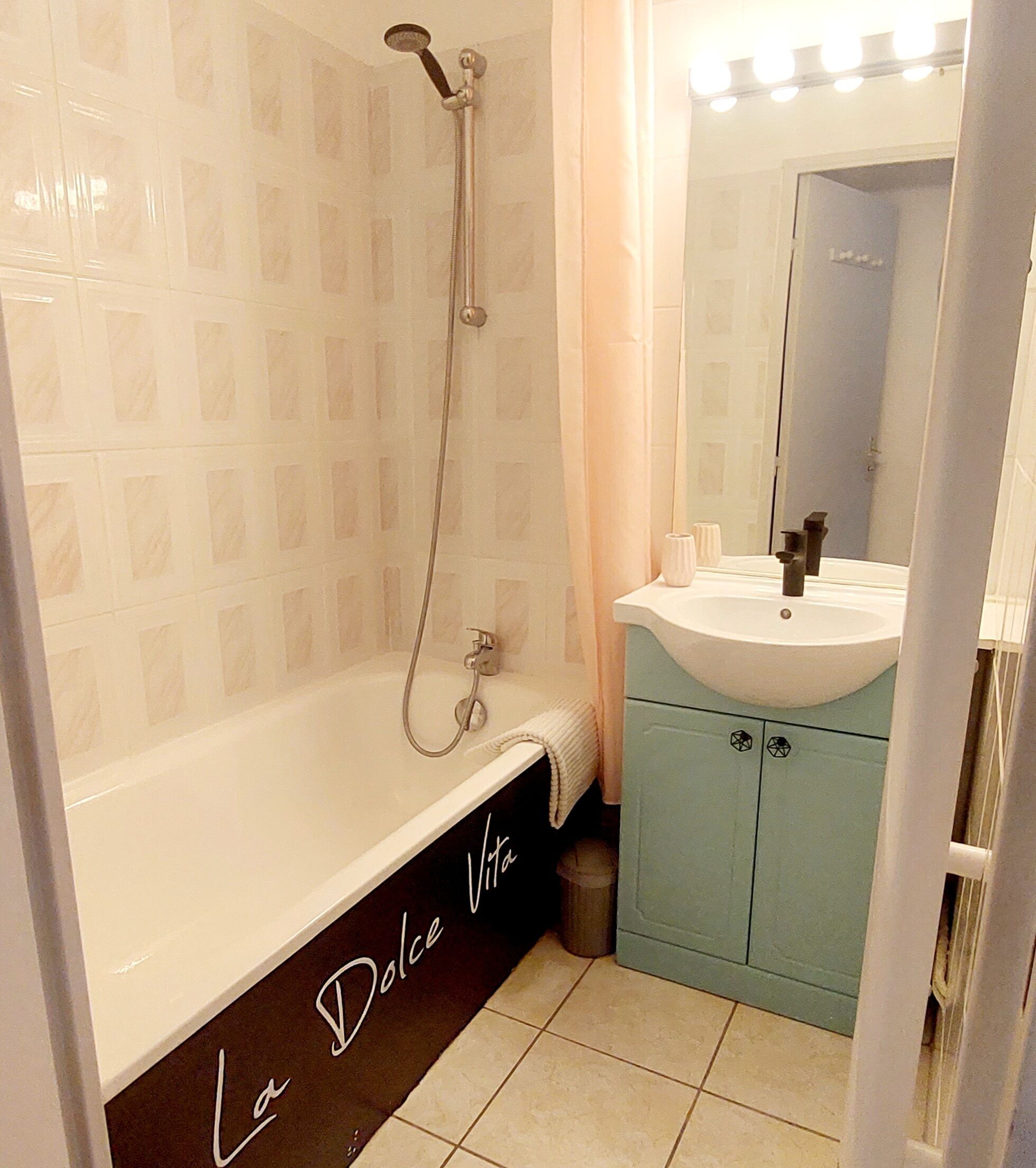 A bathroom with a white bathtub, a sink with a mirror above it, and a shower head.