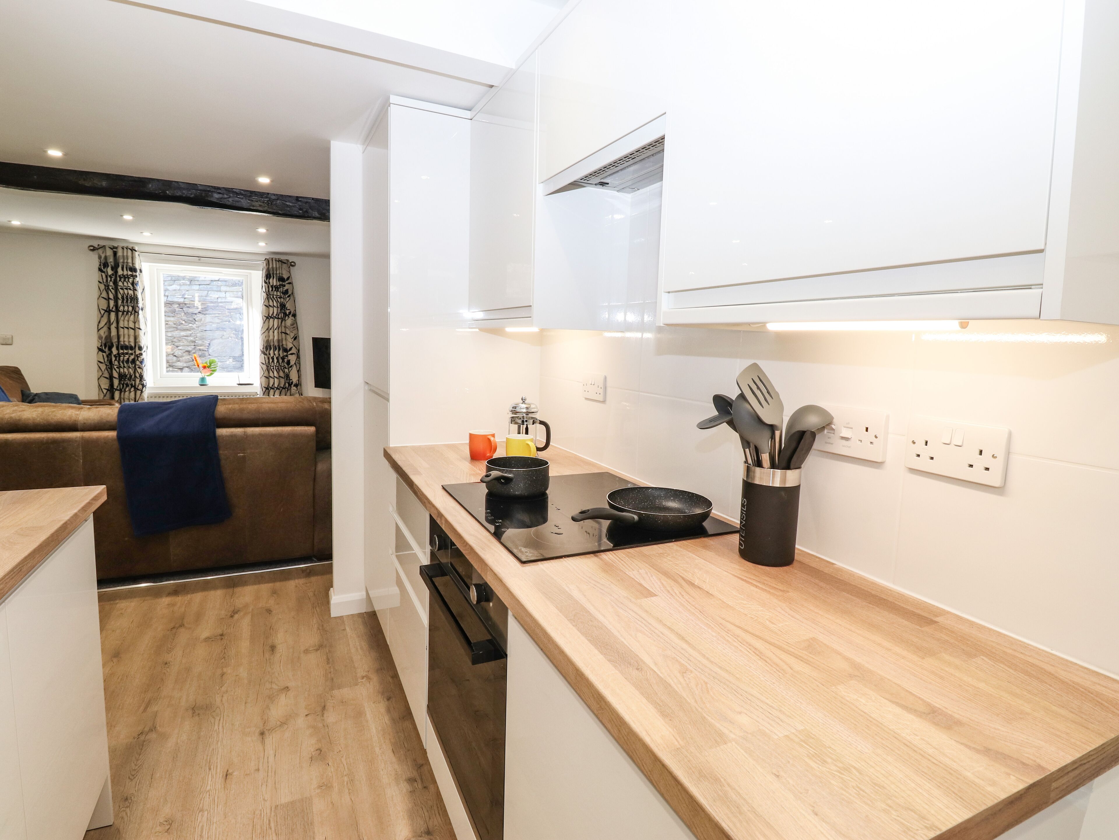 A modern kitchen with wooden countertops, a black induction cooktop, and a utensil holder.