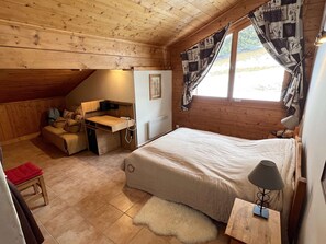 A cozy cabin room with a loft bed, a desk, and a chair.