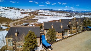 A residential area with multiple houses, a clear sky, and snow-covered hills in the background. - Granby Ranch Lookout - 3bd/2ba Ski-in/out Luxury Slope-facing Mountainside Condo (Granby)