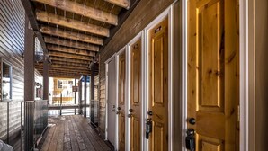 A corridor with wooden doors, numbered 114 and 116, leading to a building with a wooden exterior. - Granby Ranch Lookout - 3bd/2ba Ski-in/out Luxury Slope-facing Mountainside Condo (Granby)