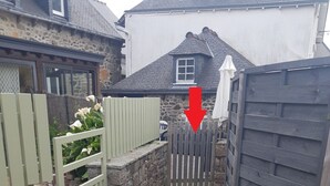 Un sendero estrecho que conduce a un muro de piedra y una puerta de madera.
