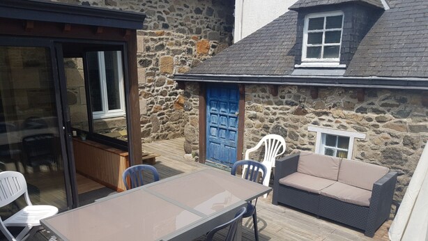 Un patio con mesa y sillas, un sofá y un muro de piedra.