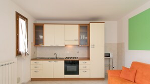 A compact kitchen with a built-in oven, a microwave, and a sink. - Apartment "Bilocale Moraiolo" with Balcony, Shared Pool & Wi-Fi (Suvereto)