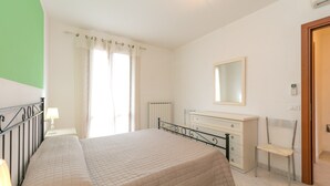 A bedroom with a bed, a chair, a dresser, and a mirror. - Apartment "Bilocale Moraiolo" with Balcony, Shared Pool & Wi-Fi (Suvereto)