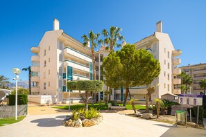 A multi-story hotel with balconies, a courtyard with trees, and a sign indicating amenities.