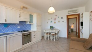Una cocina con armarios blancos, una estufa a gas y un comedor con mesa y sillas.