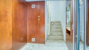A hallway with a wooden door, a glass door, and a staircase leading to an upper floor. - Pet-Friendly Apartament Luisa close to the Beach with Balcony & Wi-Fi (Lloret de Mar)