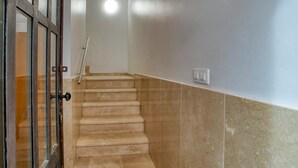A staircase with beige steps leading to a landing, a door with a glass panel, and a wall switch. - Apartment Yaco 2 near the beach with sea views and Wi-Fi (Lloret de Mar)