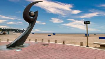 Une sculpture située sur la plage, une promenade dallée et un panneau indiquant la présence d’un accès Wi-Fi gratuit.