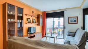 A room with a bed, a TV, a small table, a sofa, a balcony with a railing, and a wall with a picture. - Apartment Yaco 2 near the beach with sea views and Wi-Fi (Lloret de Mar)