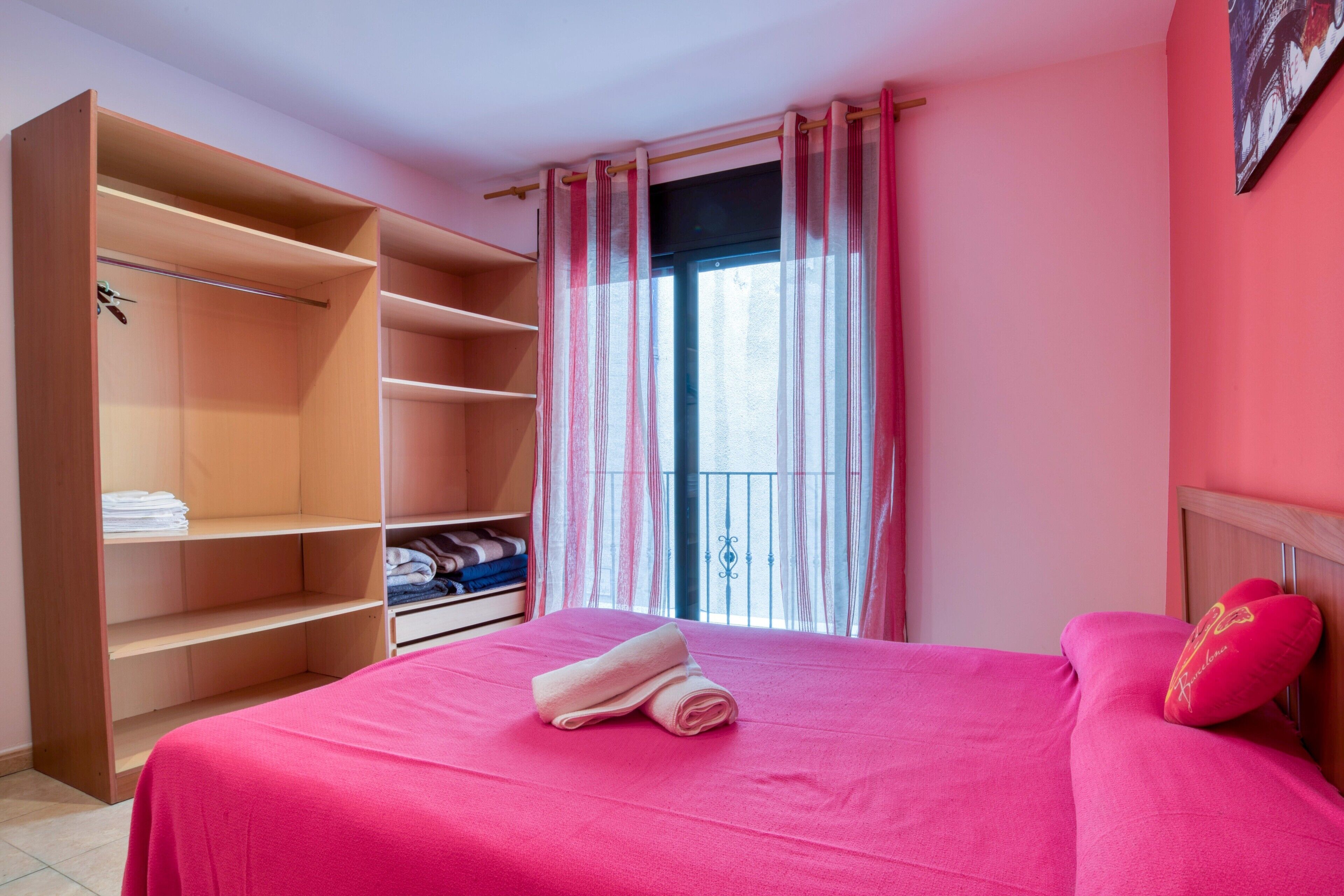A room with a bed, a large wardrobe, and a window with curtains.