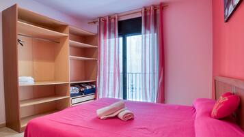 A room with a bed, a large wardrobe, and a window with curtains.