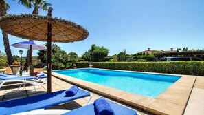 A swimming pool with lounge chairs and umbrellas, surrounded by greenery and a clear sky. - Villa 'Pantina' with Pool & Wi-Fi (Pollenca)