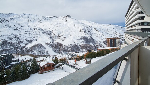 Et snedækket bjerg med skilift, bygninger og en balkon med udsigt over landskabet.