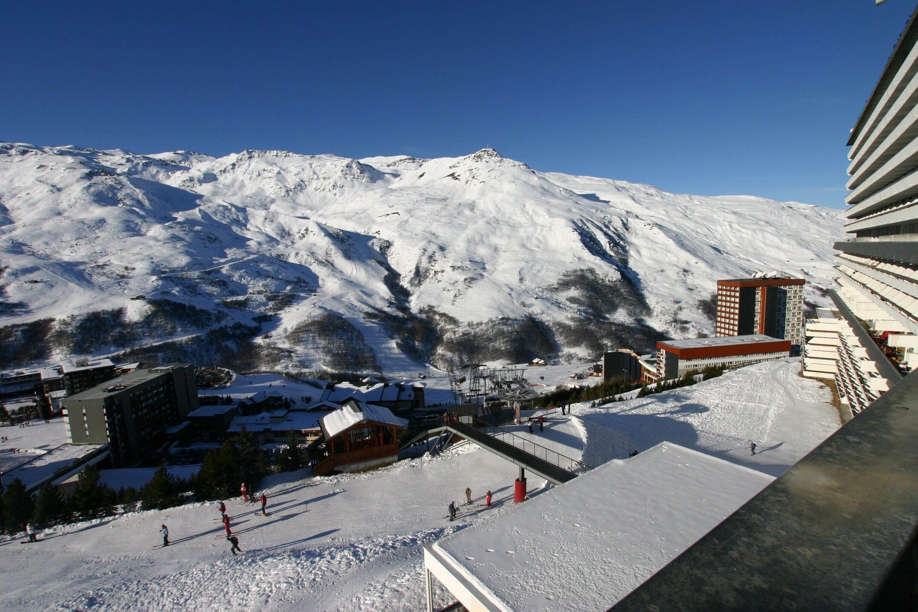 A snow-covered mountain with a ski resort, buildings, and a ski lift.